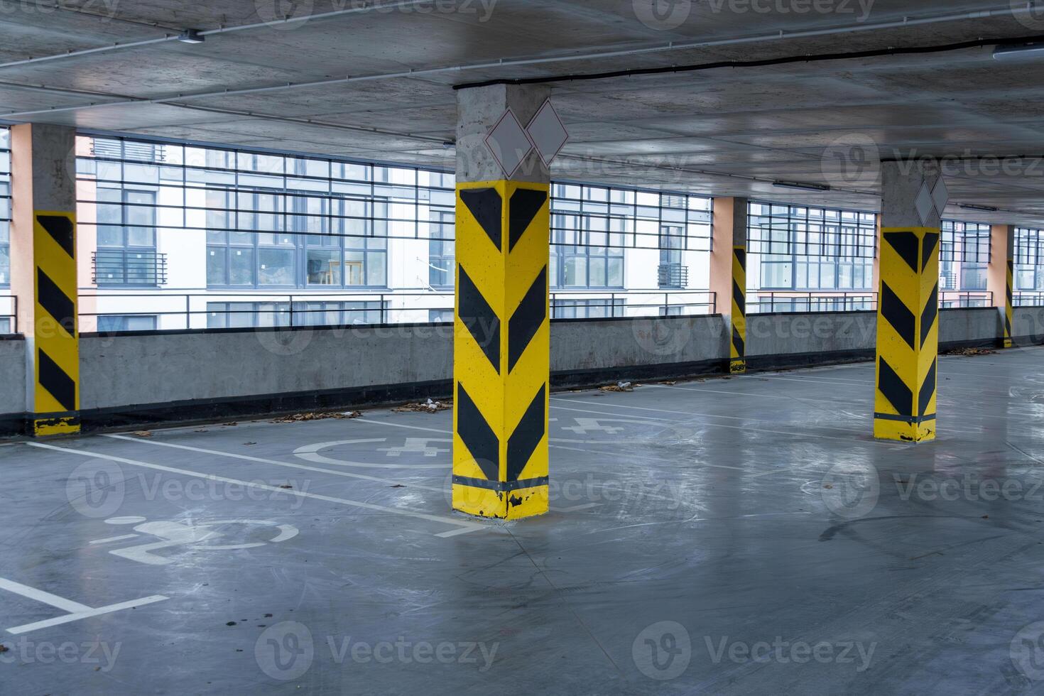 Interior view of an underground parking garage with safety markers, showcasing empty parking spaces and supporting columns photo