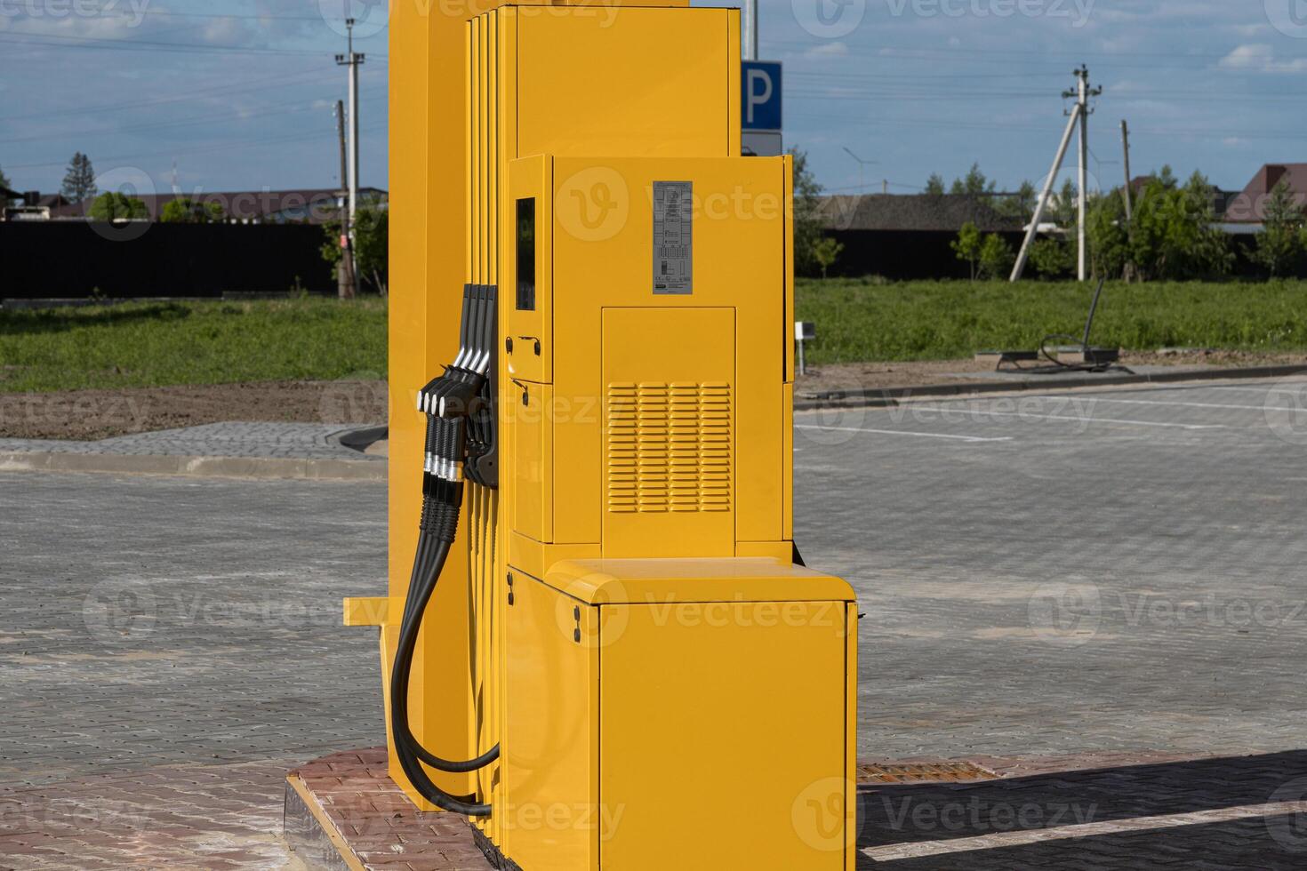 A bright yellow fuel dispenser stands alone at a gas station in a rural location, ready for vehicles to refuel photo