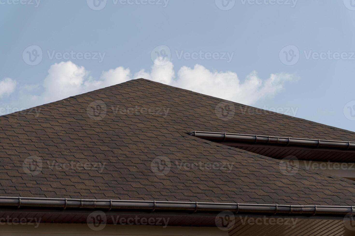 Modern tiled roof construction highlights quality workmanship on a residential house set against a bright blue sky with white clouds photo