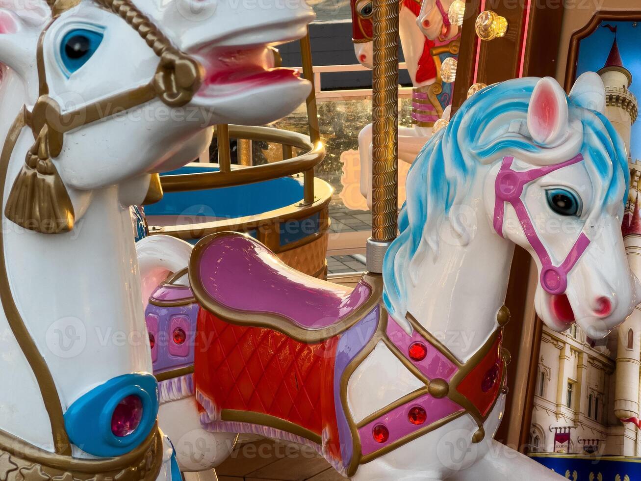Brightly painted carousel horses stand ready for children, showcasing intricate details and vibrant colors in a cheerful amusement park photo