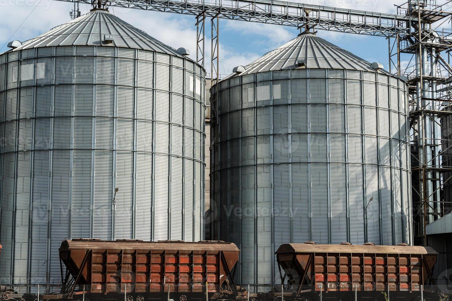 Large silos stand tall at a grain storage facility, where harvested crops are stored for future use. The sun brightens the industrial scene photo