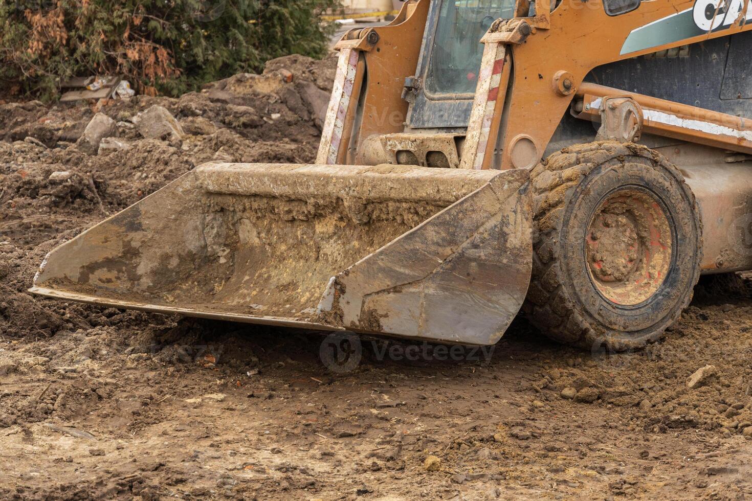 Heavy machinery works on earthmoving tasks at a construction site covered in mud and debris under overcast skies photo