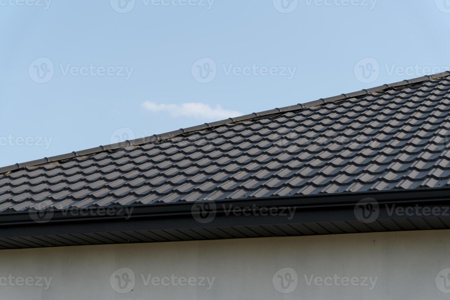 Close-up view of a modern tiled roof against a clear sky, highlighting the intricate patterns and textures of the roofing material photo