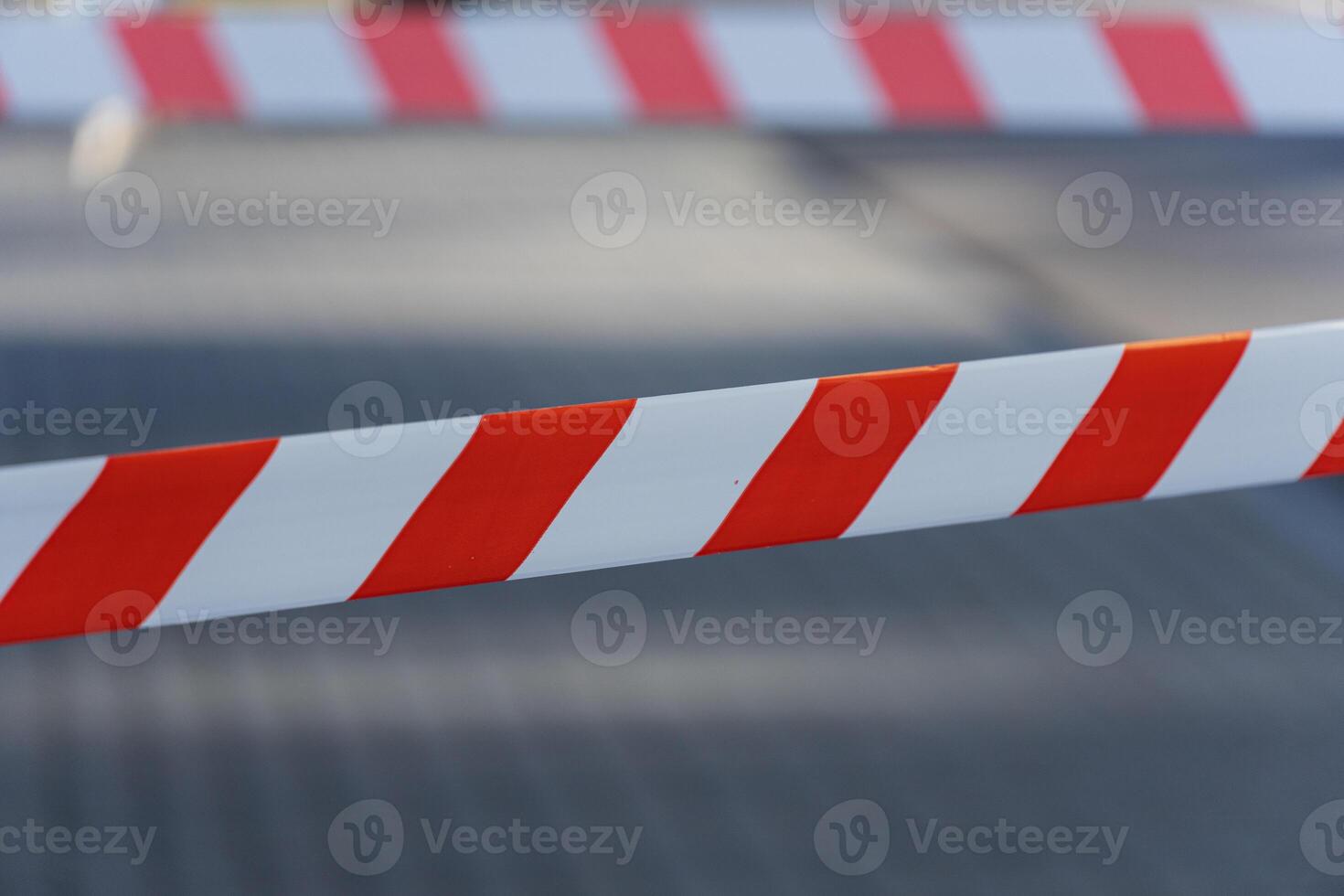Striped barrier tape in red and white prevents access to a specific location during daylight in an outdoor urban area photo