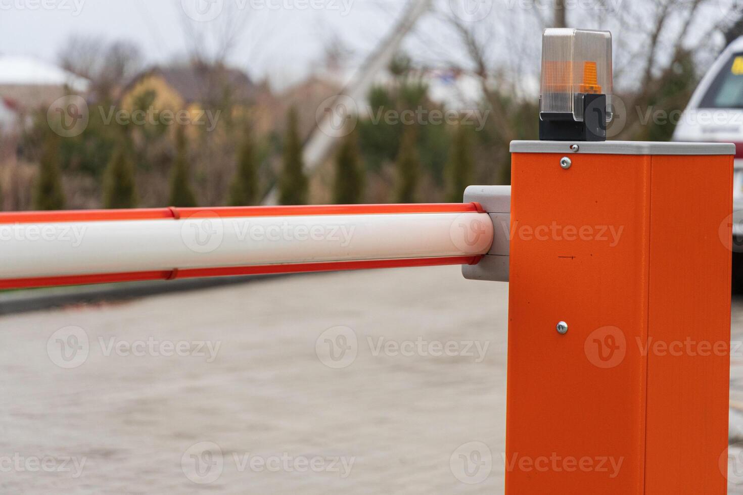 A security barrier stands at the entrance of a parking lot, ensuring controlled access to vehicles in a suburban neighborhood on a cloudy day photo