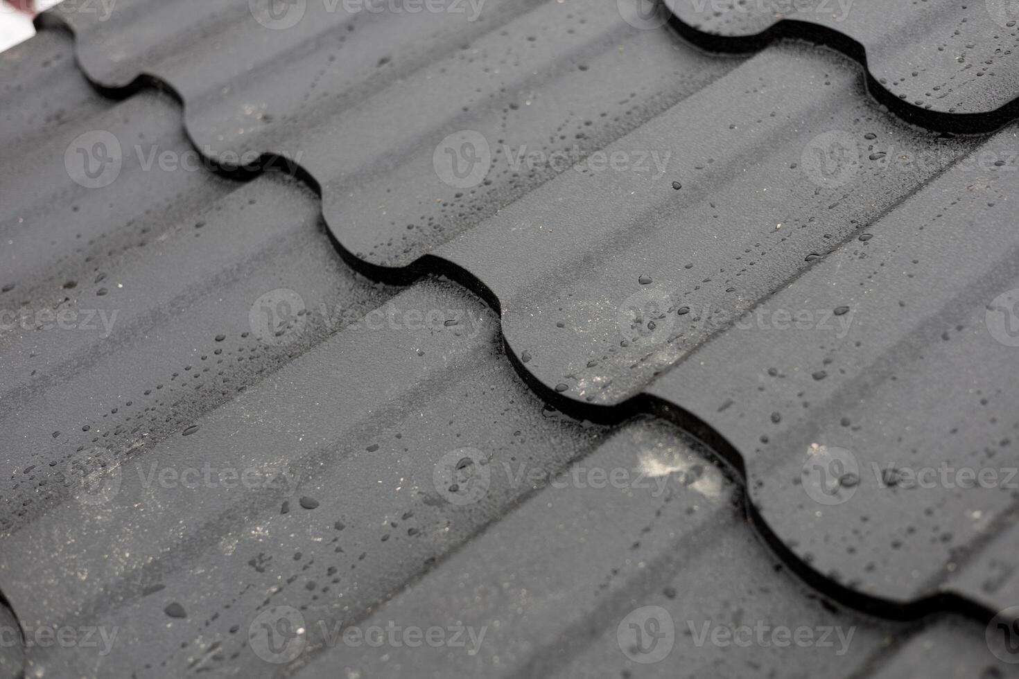Dark roof tiles are covered with droplets of rainwater after a light rain in a city during the afternoon, showcasing the weather effects on roofing photo