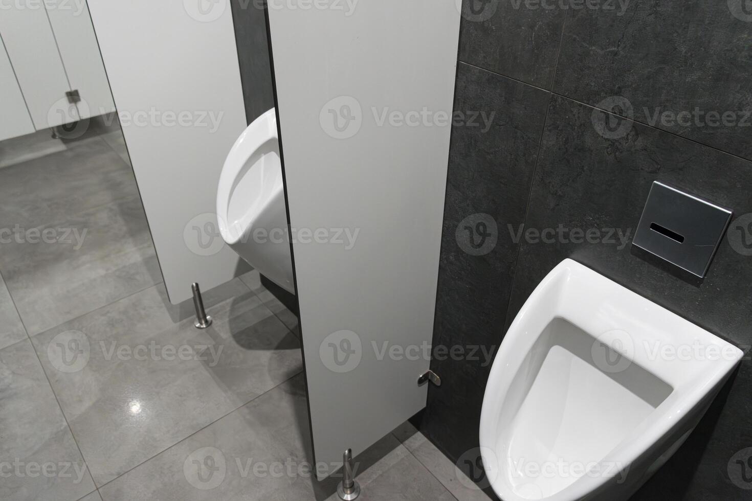 Clean and minimalist restroom design showcases white urinals beside privacy partitions in a contemporary urban environment photo