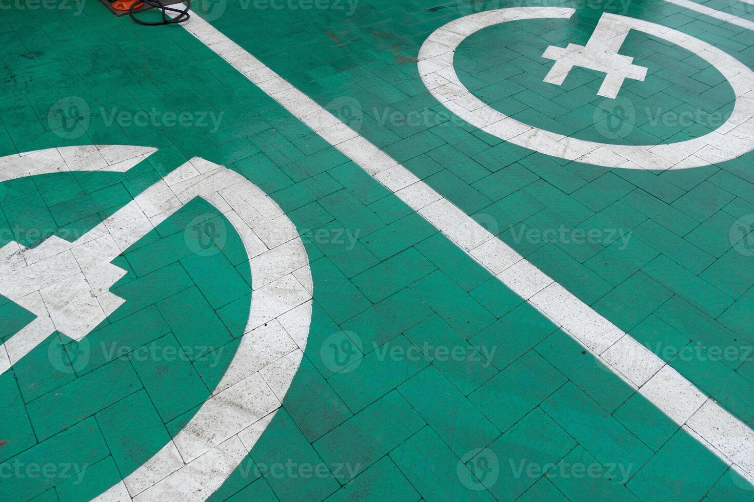 Clear markings on a green parking area designate spaces for electric vehicles and bicycles, promoting eco-friendly transportation options photo