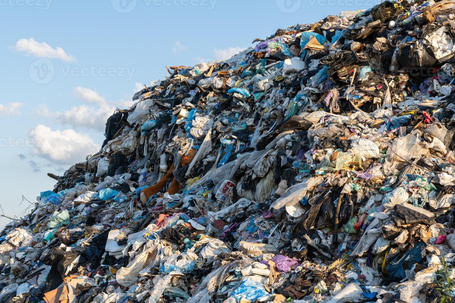 A vast heap of discarded plastic materials looms against the horizon, reflecting humanity's struggle with waste management and pollution photo