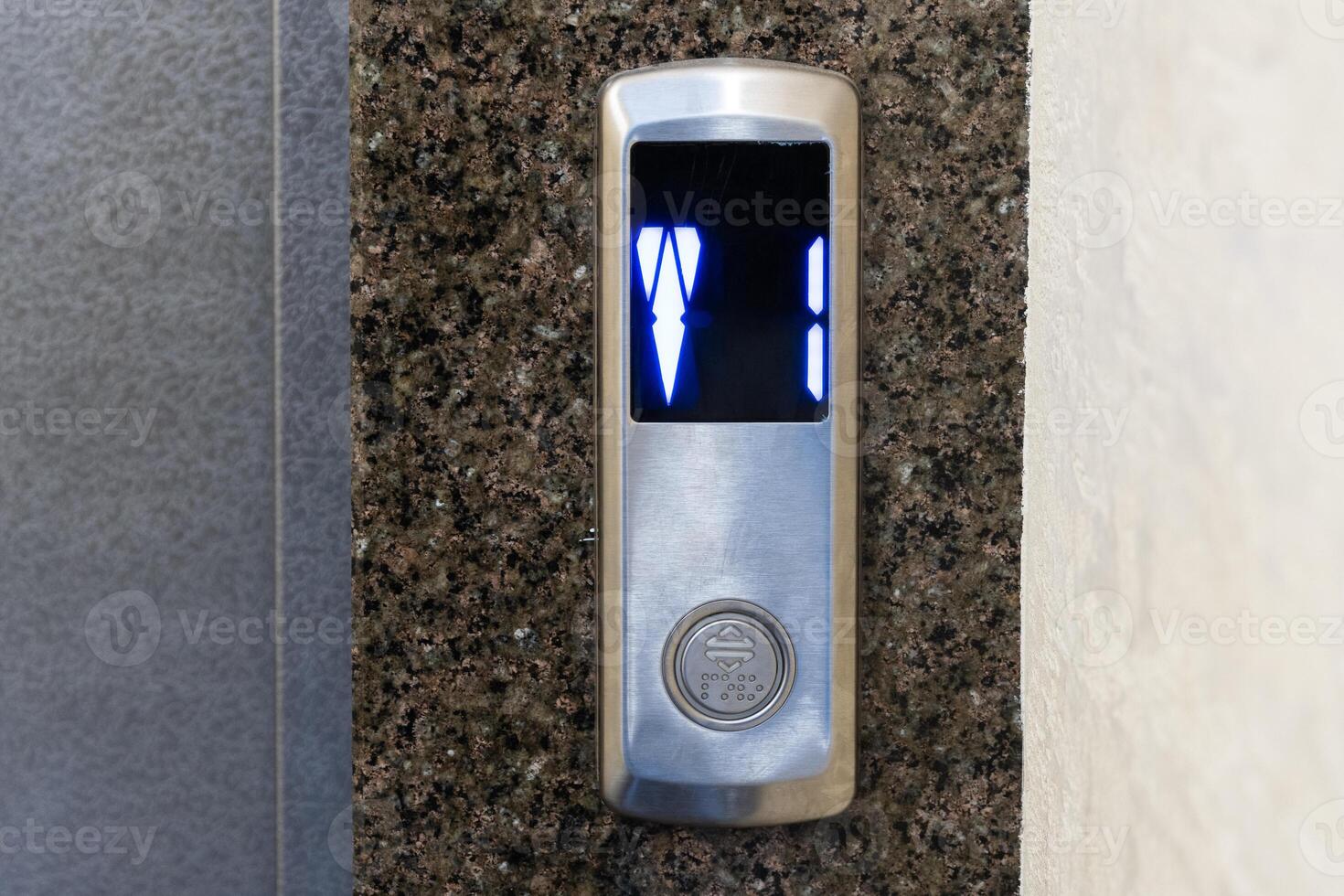 Digital numbers illuminate as the elevator waits for passengers in a modern office building's sleek lobby during peak hours photo