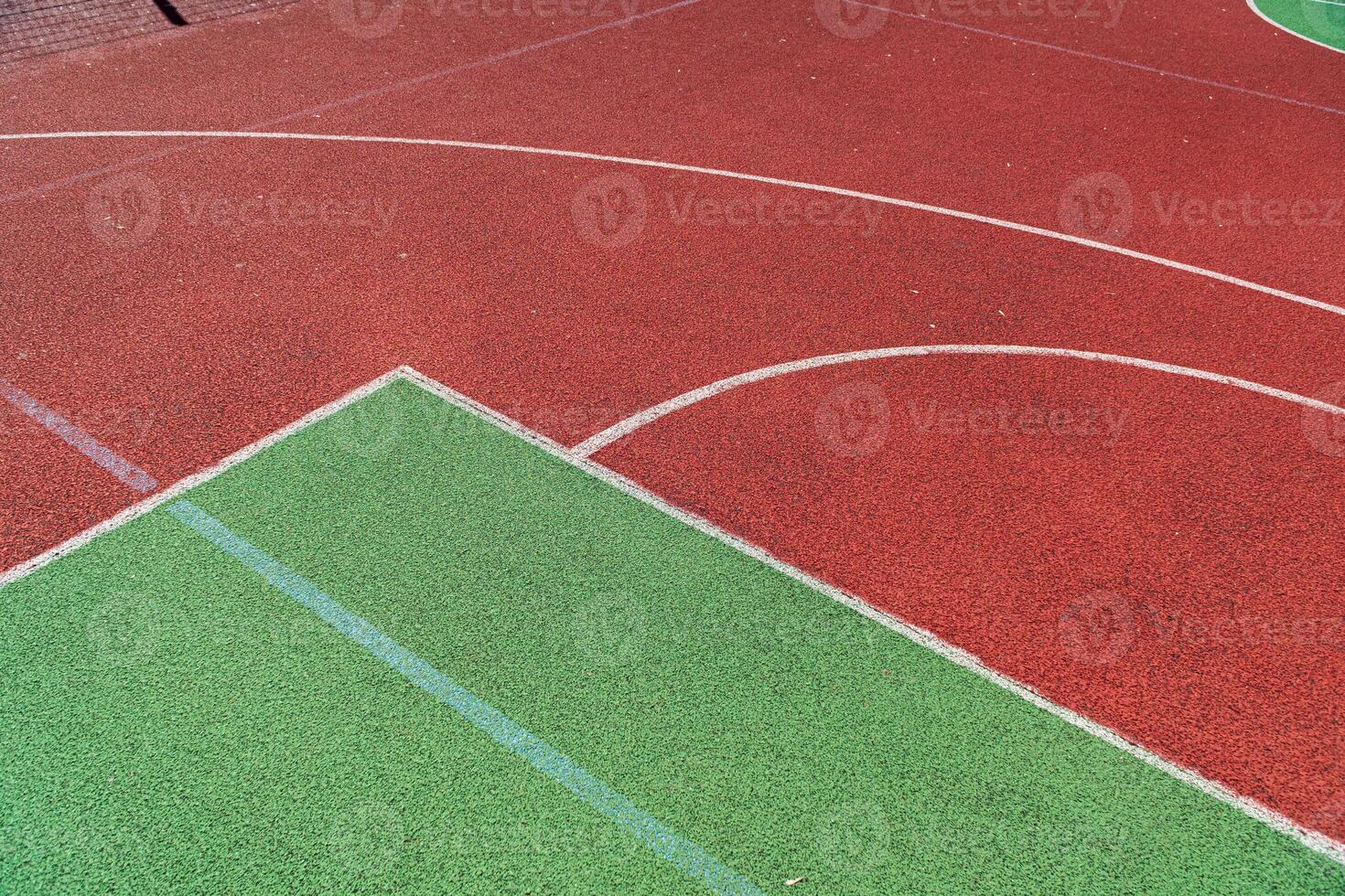 Brightly colored sports court features a mix of red and green surfaces, offering a lively backdrop for athletic activities on a sunny day photo