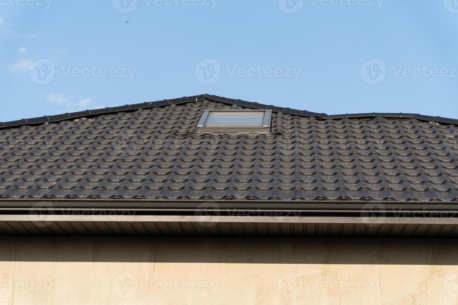 A residential building with a distinct rooftop design hosts a skylight, illuminated by the bright blue sky above photo