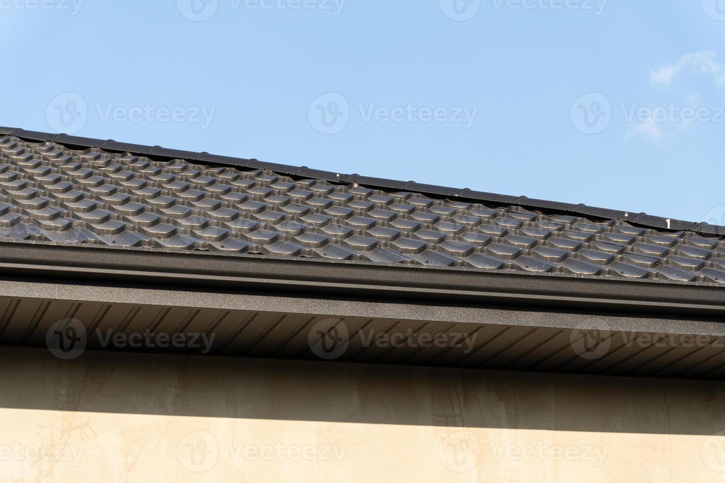 Textured roofing material on a modern home reflects sunlight under a clear blue sky, showcasing craftsmanship and design elements photo