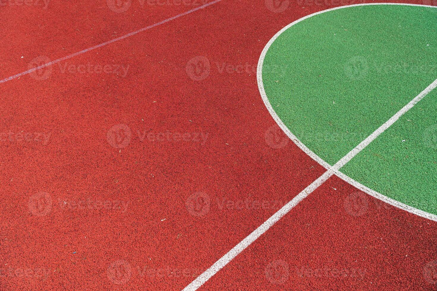 Vibrant basketball court featuring a red surface and a green half-court area, perfect for sports activities and community events photo