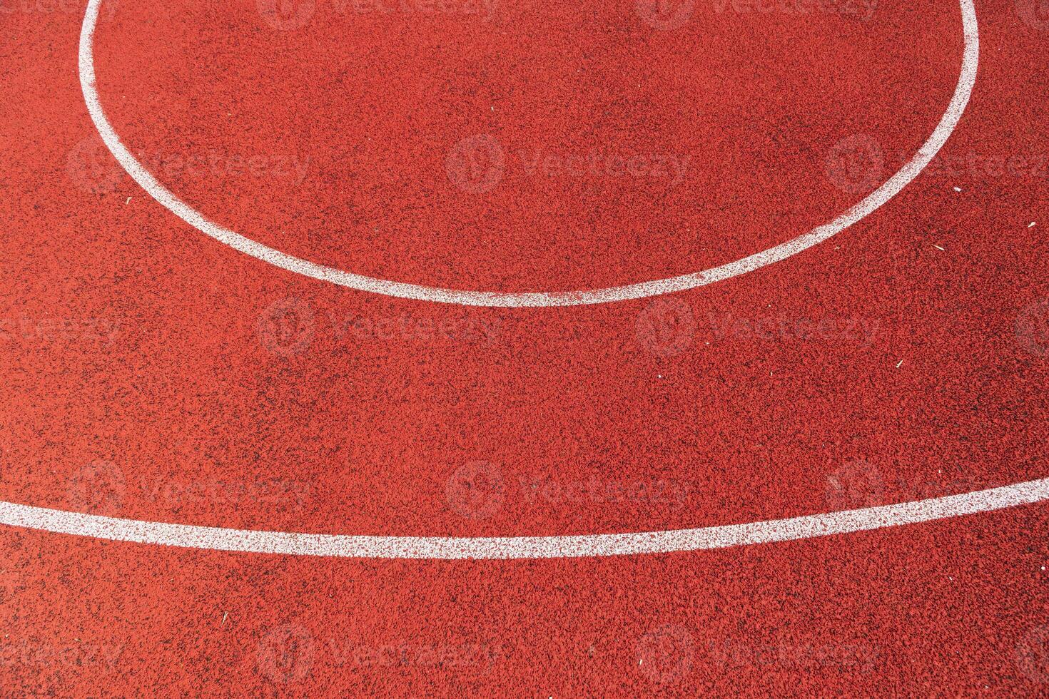 Smooth red track surface features clean white lines forming a perfect circle under clear blue skies, inviting athletes to train photo