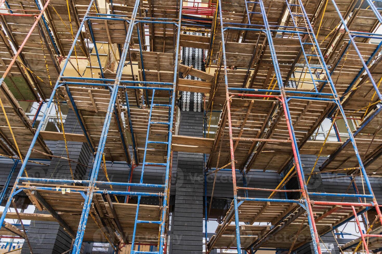 Workers navigate complex scaffolding structures as construction progresses in a busy urban area during midday photo