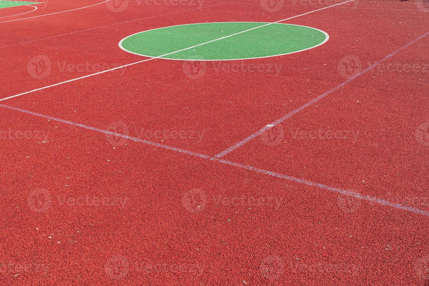 The vibrant red sporting surface features large green circles, ideal for various outdoor activities under clear blue skies photo