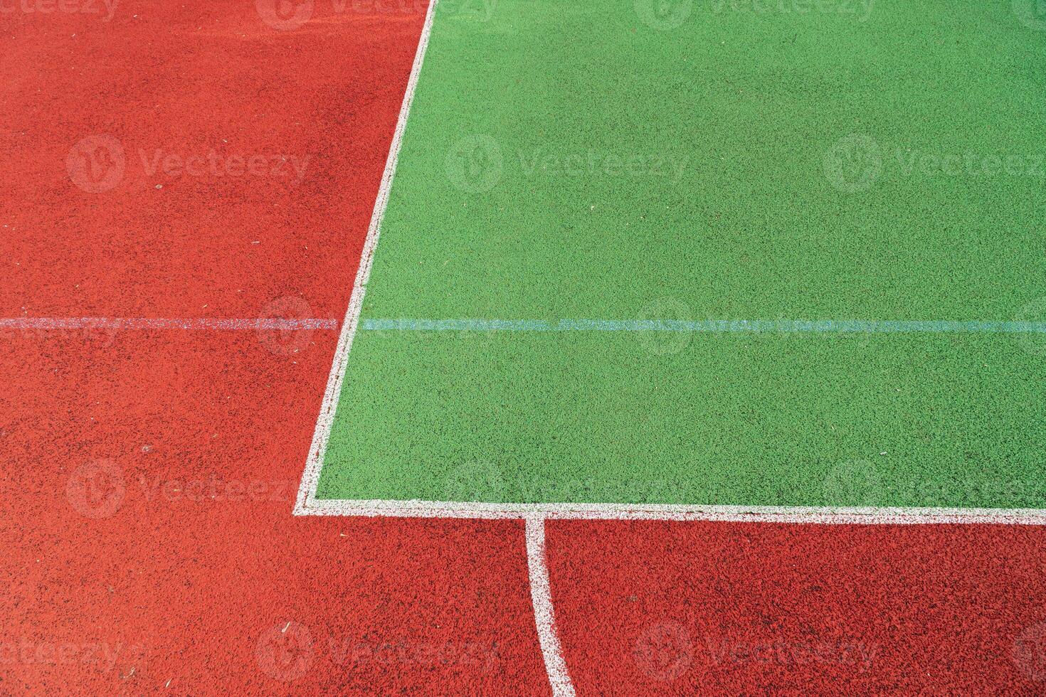 Two distinct sections of a sports court show bright red and green surfaces, lined with white markings under sunny conditions photo