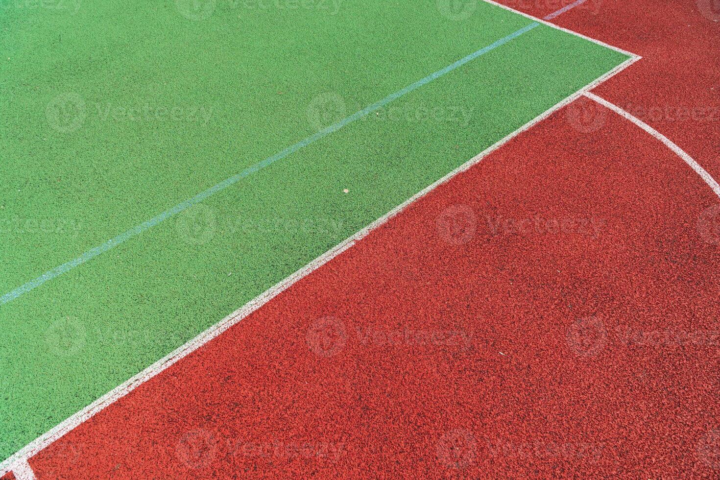 A vibrant sports court featuring distinct green and red sections ideal for basketball, tennis, and other outdoor games photo