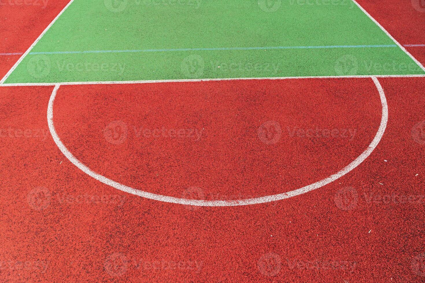 A vividly colored sports court features a bright green playing area surrounded by a bold red surface with clear white markings photo