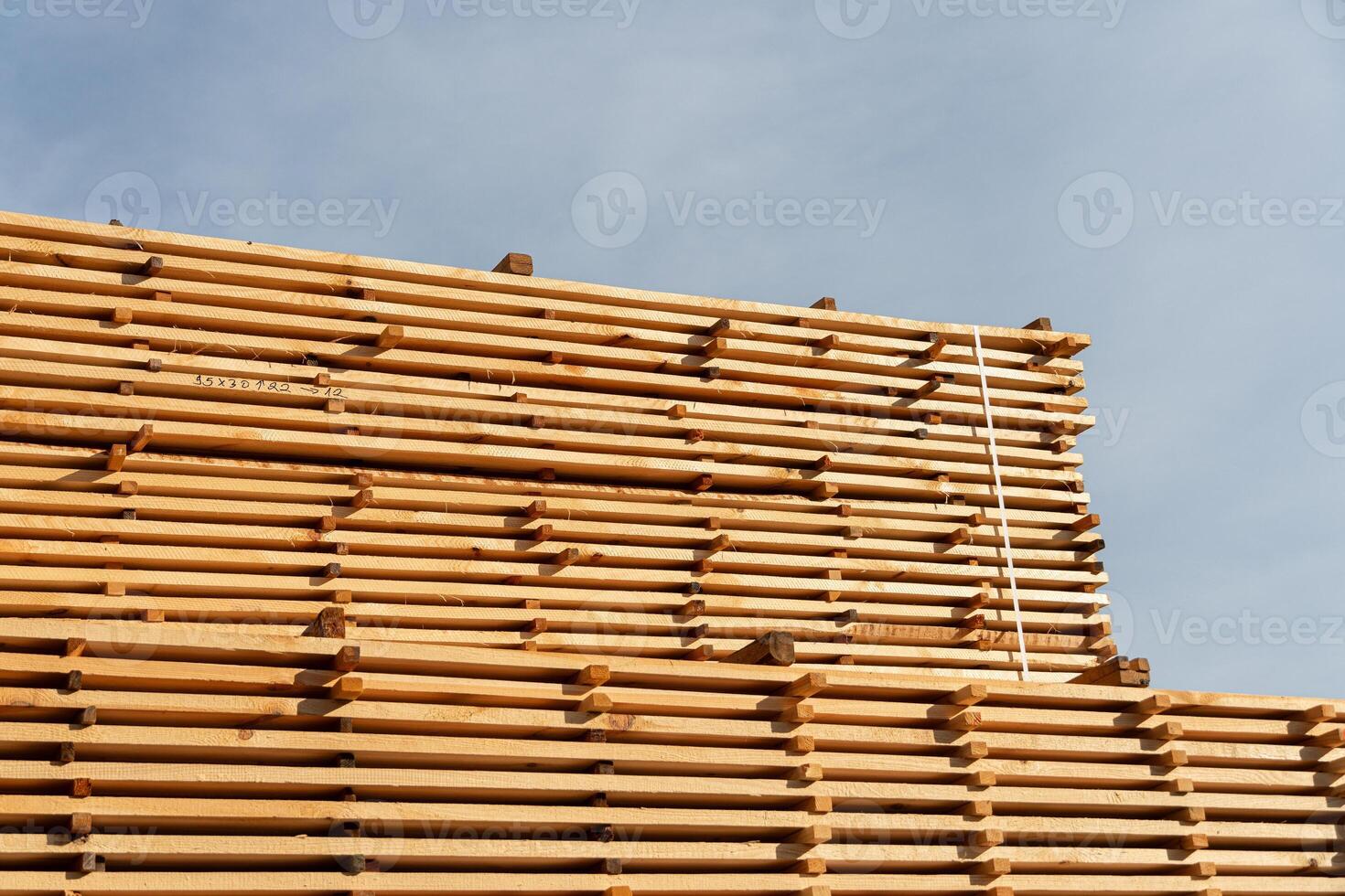 Wooden planks are carefully stacked in a lumber yard, showcasing the craftsmanship and organization of the materials in clear weather photo