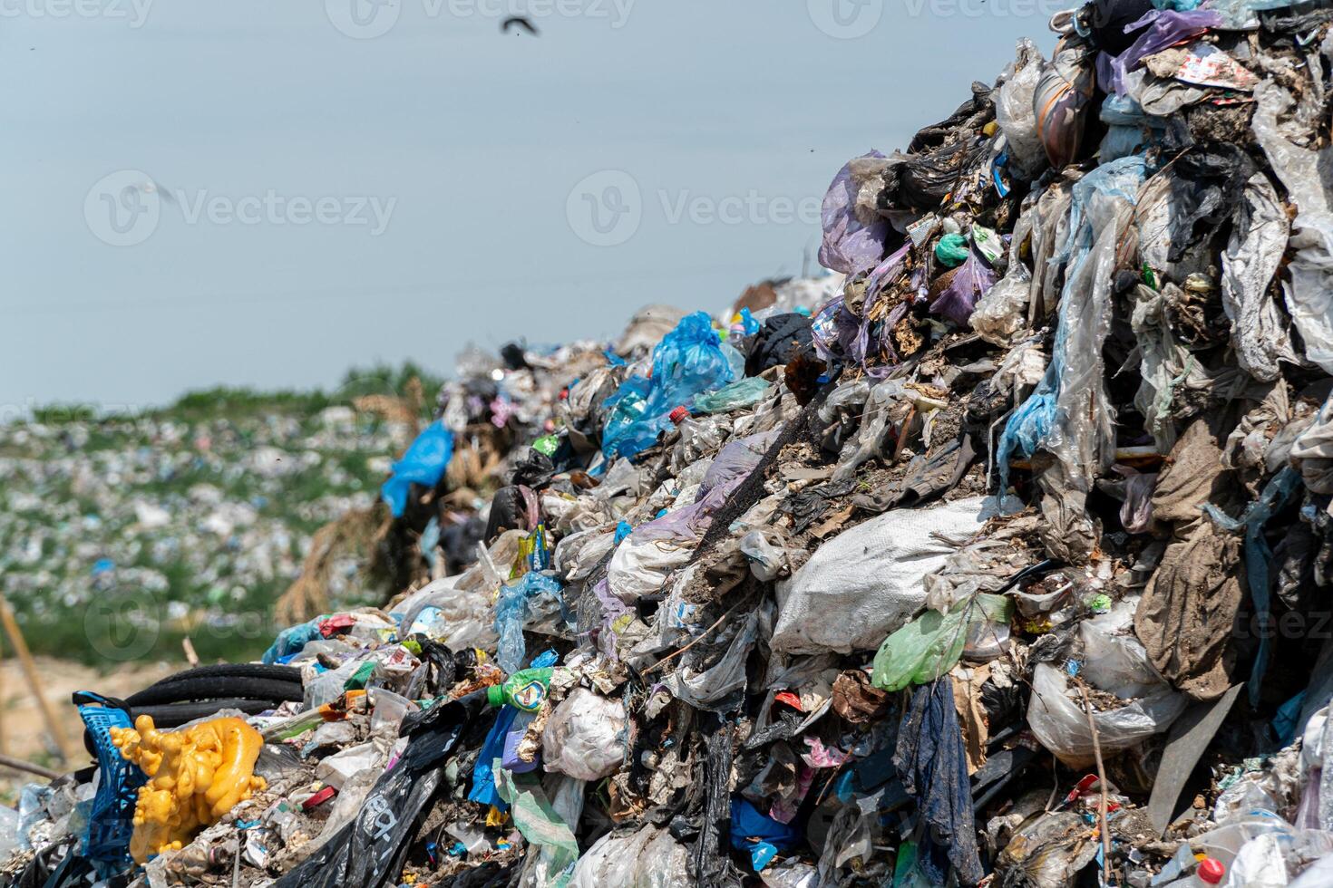 A massive heap of assorted garbage accumulates under clear skies, showcasing the ongoing challenge of waste disposal and recycling photo
