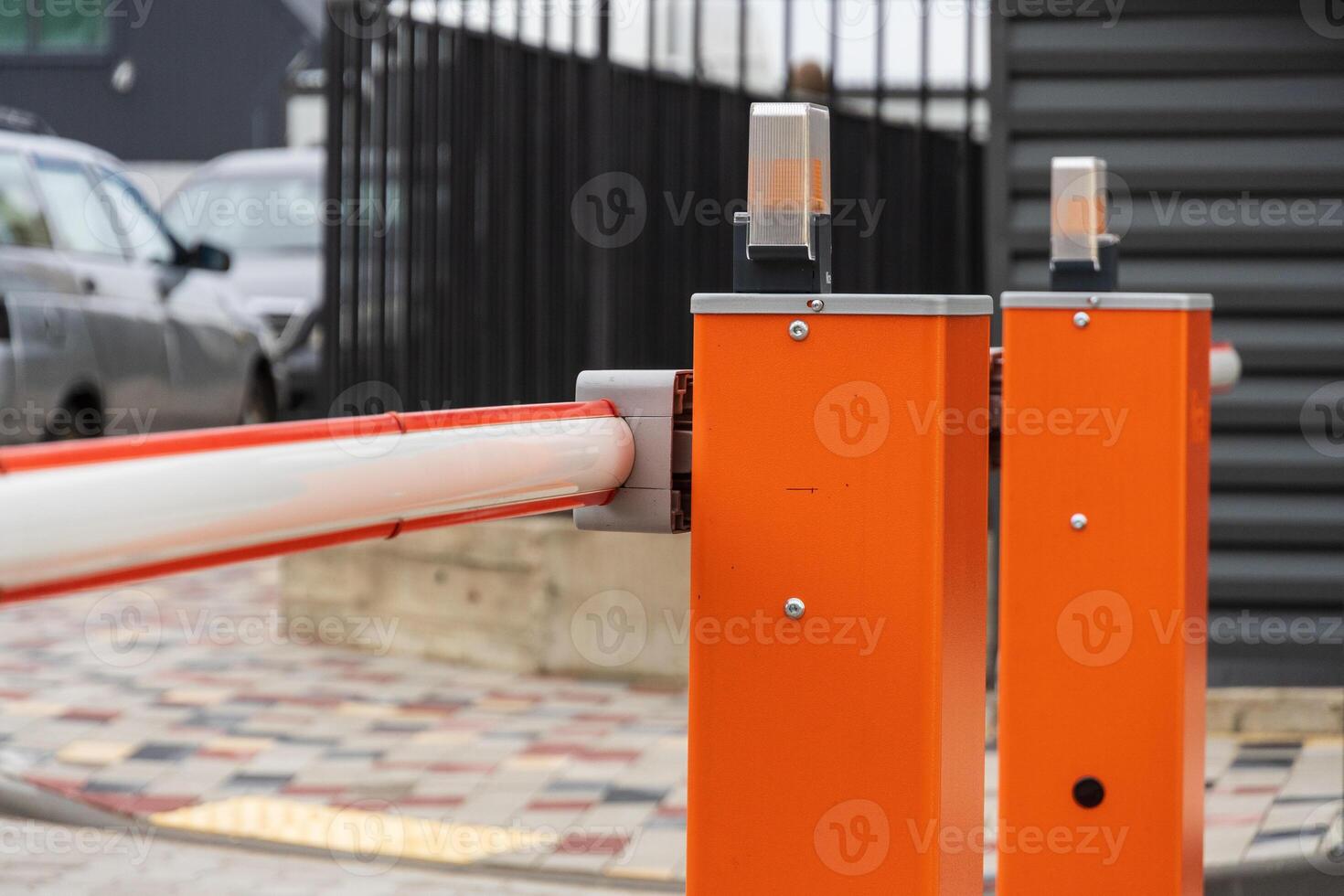 An automatic barrier gate stands closed, controlling entry to a well-organized parking lot, ensuring safety and security for vehicles photo