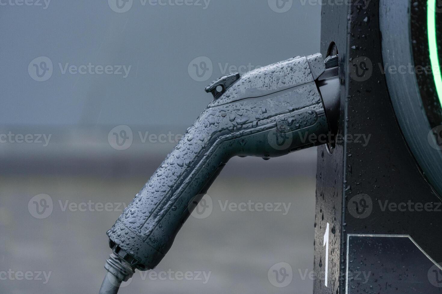 Raindrops glisten on an electric vehicle charging handle, highlighting a commitment to sustainable energy and modern transportation in cities photo