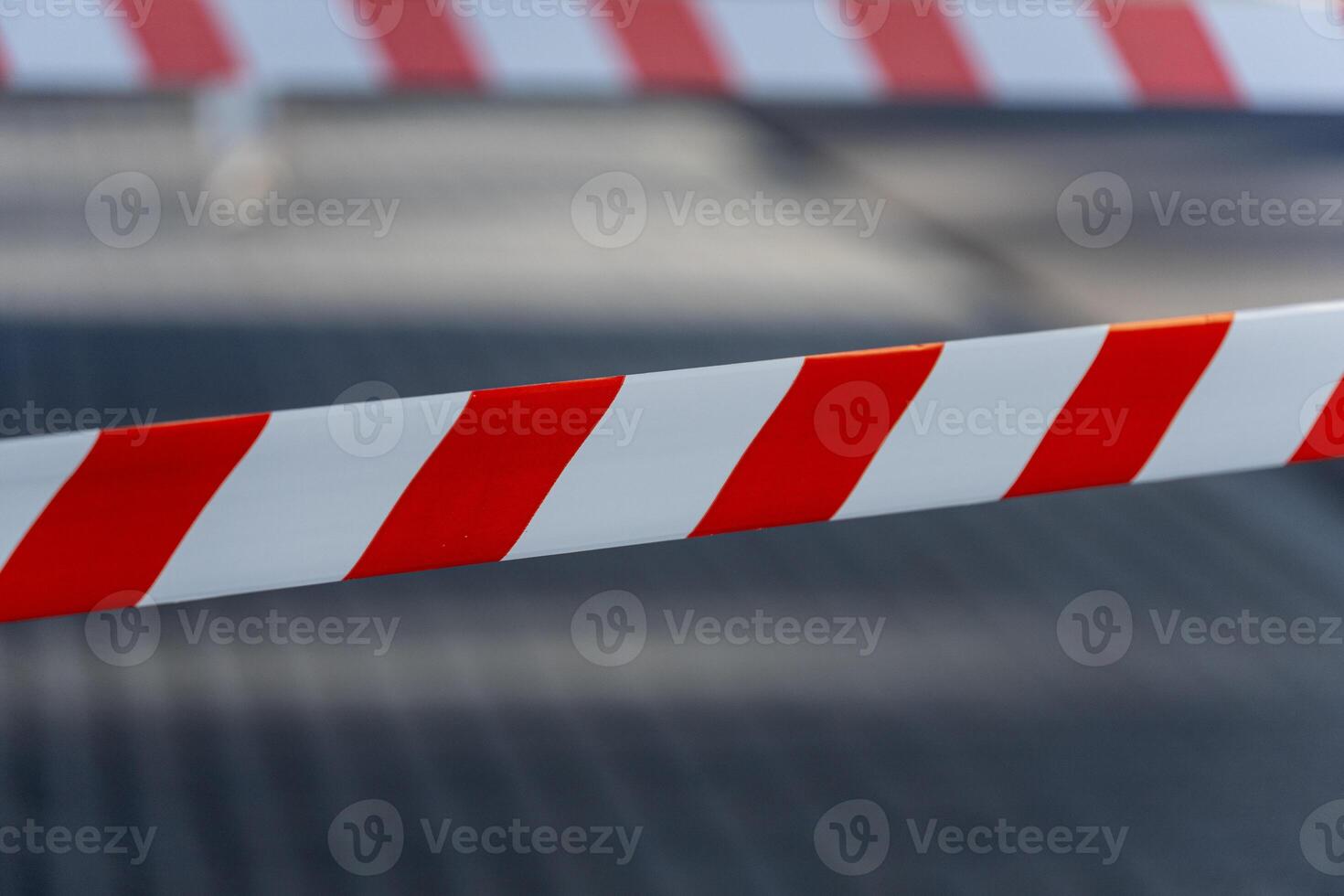 Bright striped caution tape warns pedestrians of danger and restricted access in a bustling city environment during daylight hours photo