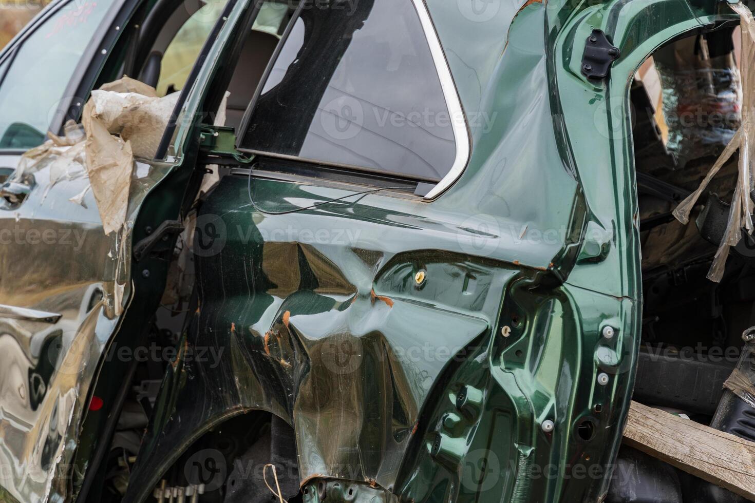 A green car involved in a severe crash displays significant structural damage, highlighting the dangers of traffic accidents photo