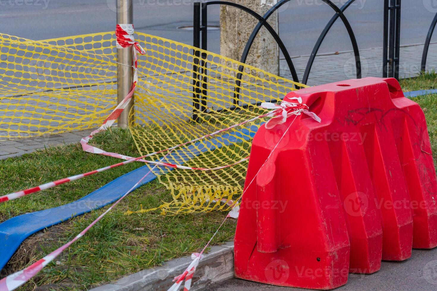 Construction work is in progress in the city, marked by a red barrier and caution tape to ensure pedestrian safety near the site photo