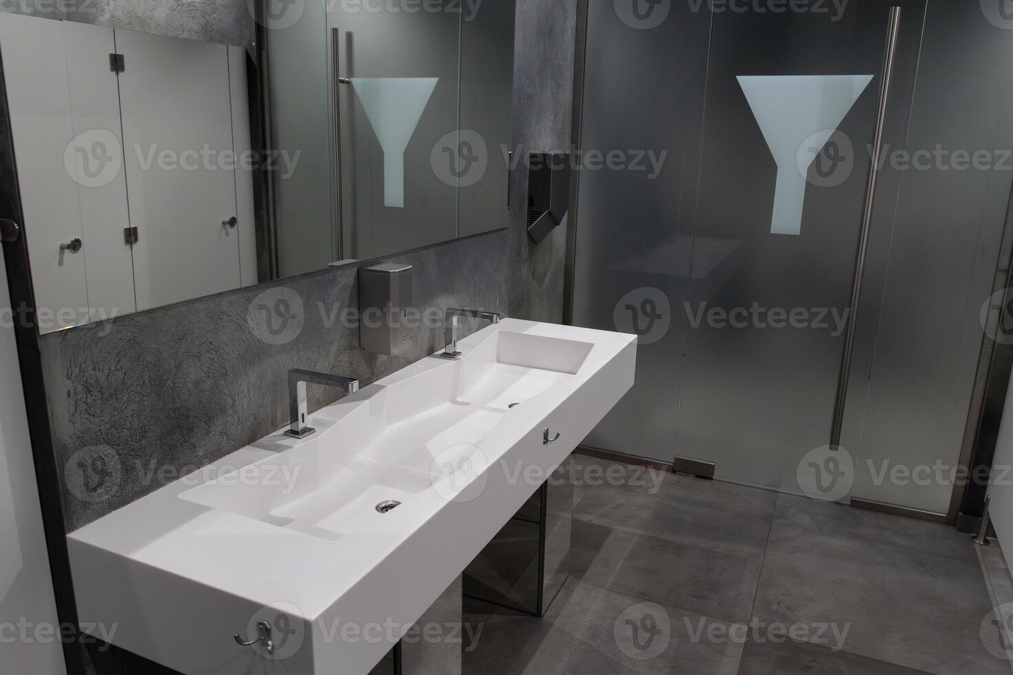 Modern bathroom showcases a spacious layout with minimalist design elements, featuring dual sinks and frosted glass for privacy photo