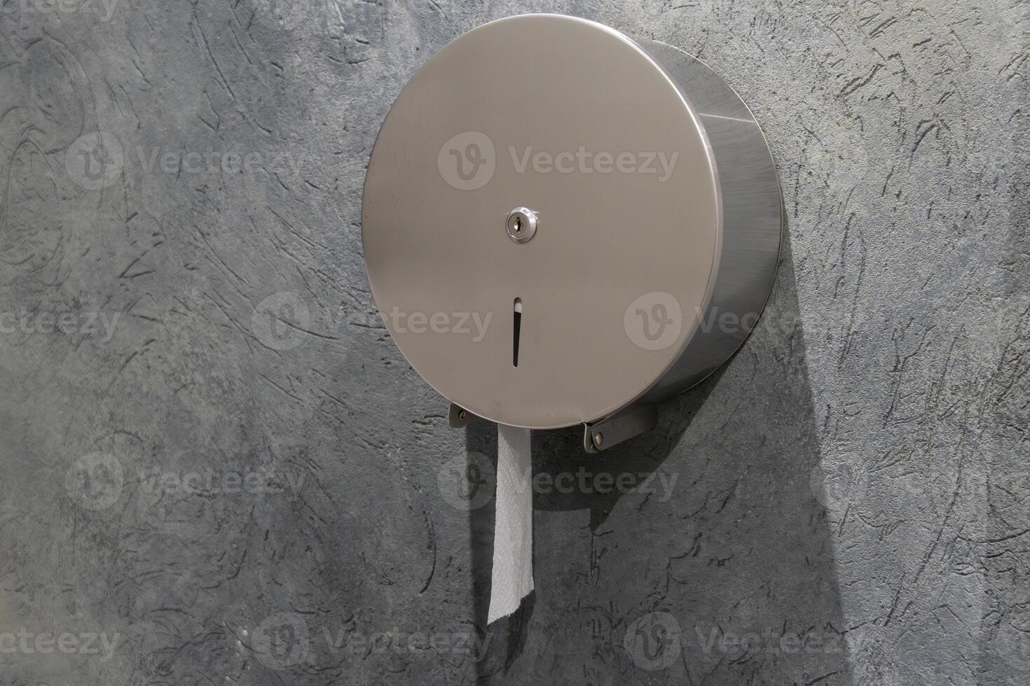 This stainless steel hygiene supply dispenser is mounted on a gray wall in a clean public restroom, promoting sanitation and easy access photo