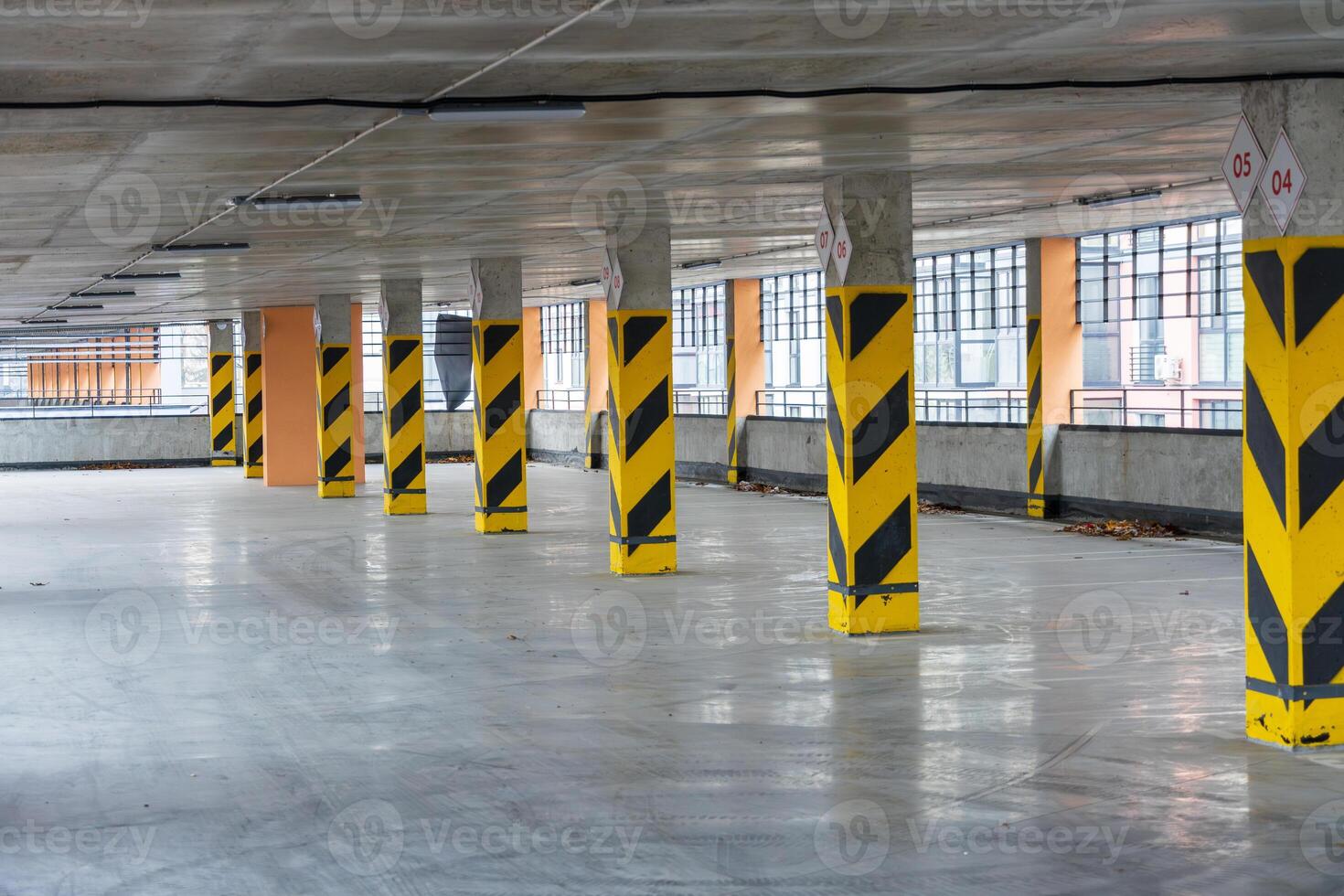 Spacious indoor parking area featuring yellow striped columns, designed for efficient vehicle storage and access in an urban setting photo