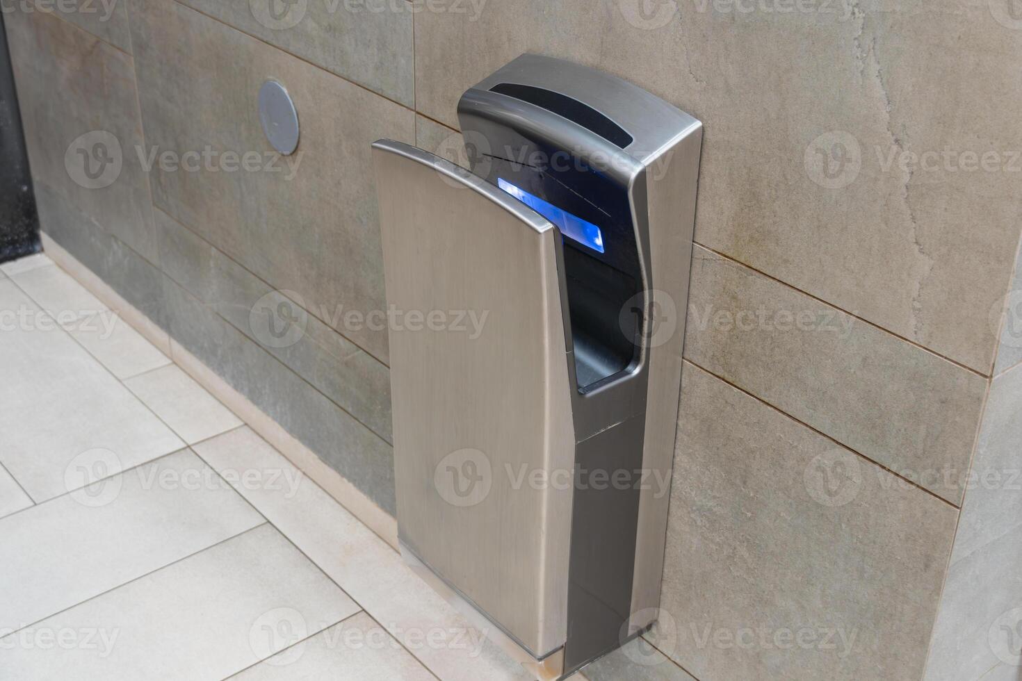 An automatic hand dryer installed in a contemporary bathroom setting promotes hygiene and efficiency for users after washing hands photo