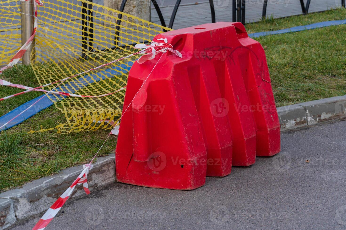 Bright red construction barrier and caution tape indicate a work zone, keeping pedestrians safe from ongoing city infrastructure maintenance photo