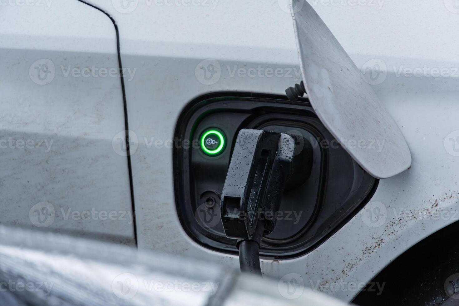 An electric vehicle connects to a charging station, showcasing the technology for sustainable transportation in action during the day photo