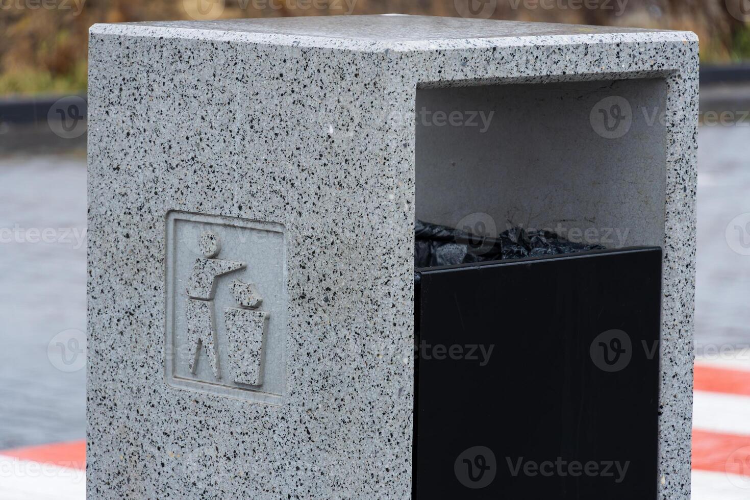 A concrete trash bin stands prominently, promoting proper waste management and recycling in an urban area, demonstrating environmental care photo
