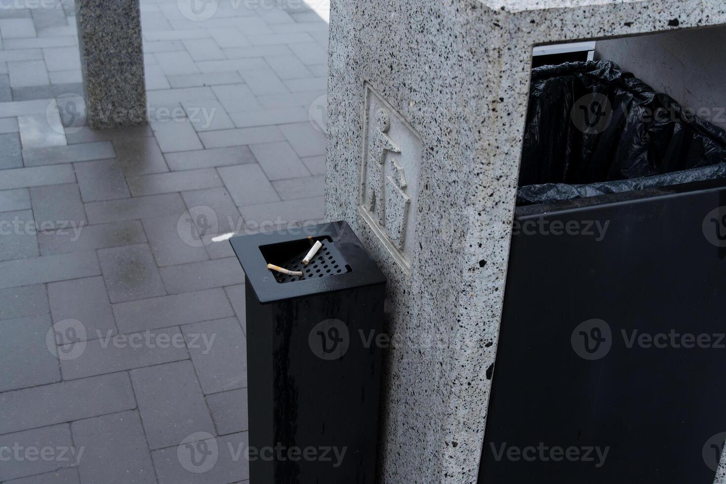 A public space features a solid waste container with a designated area for cigarette disposal, promoting environmental conservation efforts photo
