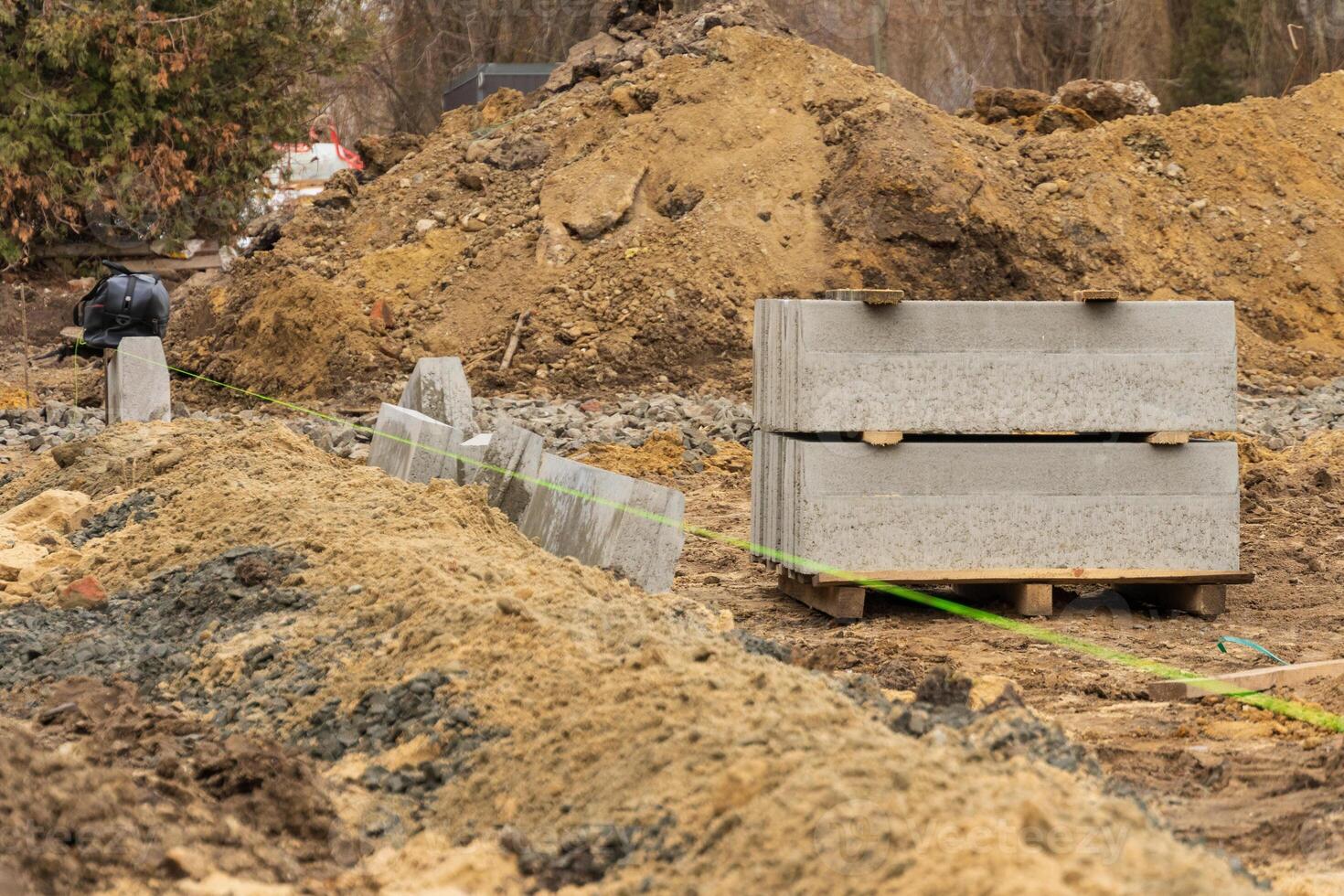 Gravel and concrete blocks line a city street construction area where landscaping and repairs are in progress, showcasing industry activity photo
