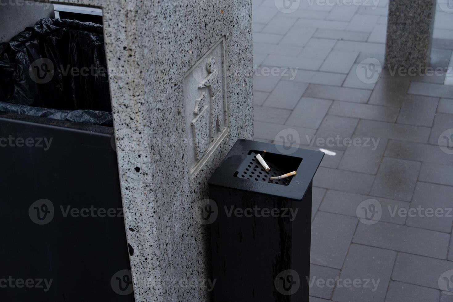 A dark trash bin stands beside a recycling container, emphasizing effective waste management and environmental conservation in the city photo