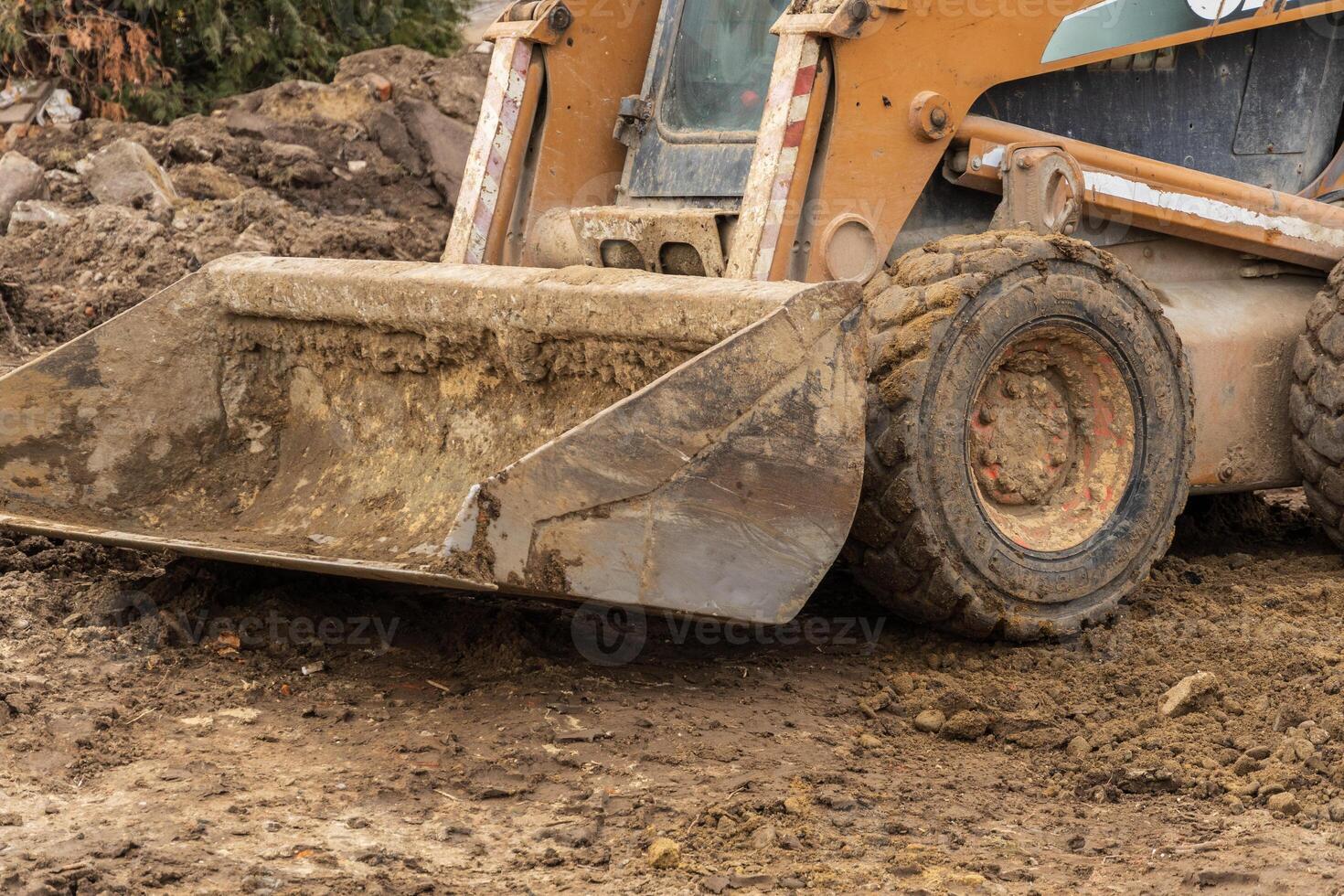Heavy machinery, including a backhoe, is actively digging and transporting soil at a construction site surrounded by dirt and debris photo