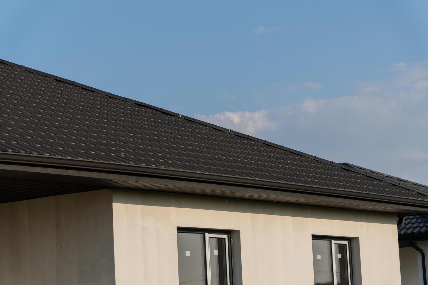 A newly installed roof on a contemporary home is shown against a clear blue sky, highlighting its sleek design and architecture photo