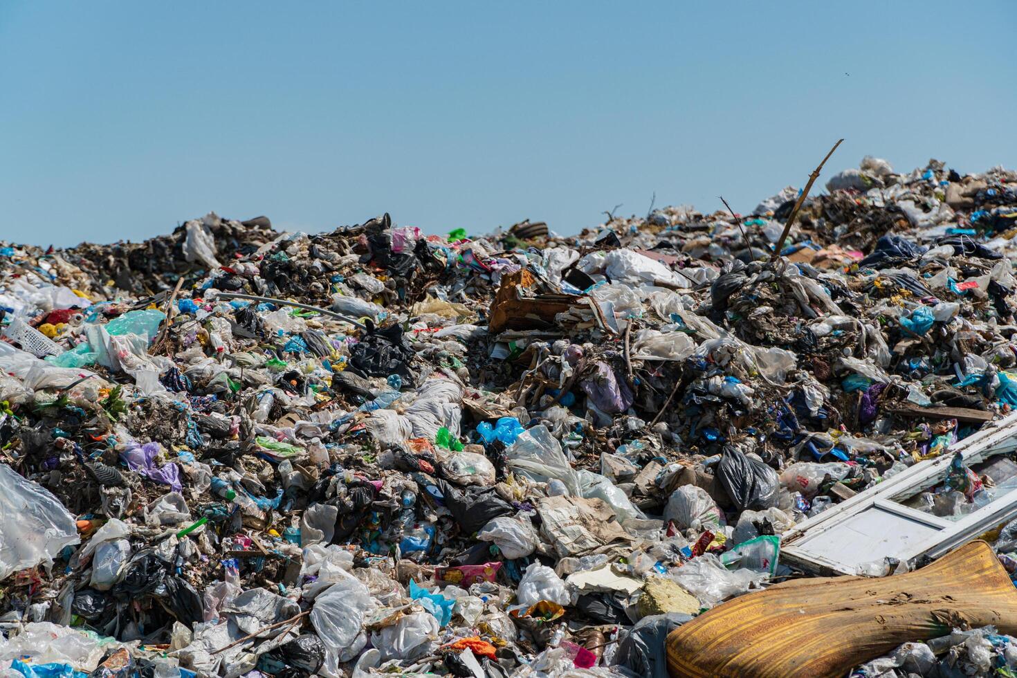 Piles of garbage and plastic debris cover the landfill, emphasizing ongoing waste management issues and the impact on the environment photo