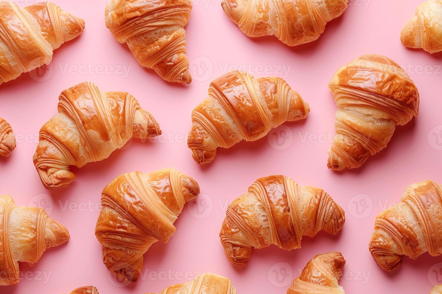 Top view pattern of fresh croissants arranged on pastel pink background, ideal for bakery branding and packaging design photo