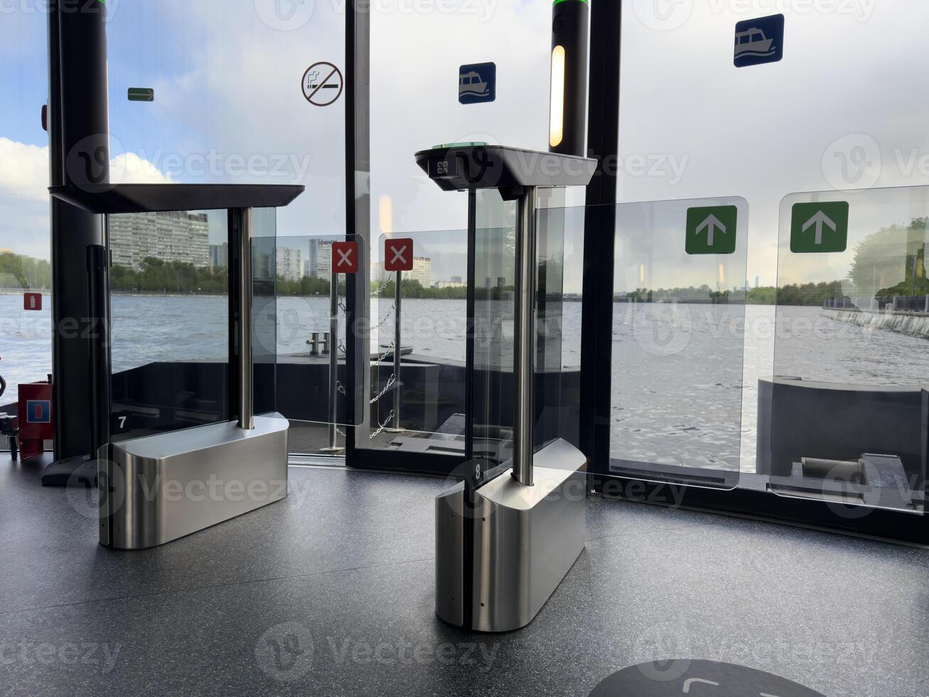 Modern turnstiles and glass exit gates inside river transport terminal with panoramic view of the water. Smart public transport infrastructure for urban mobility and seamless boarding photo