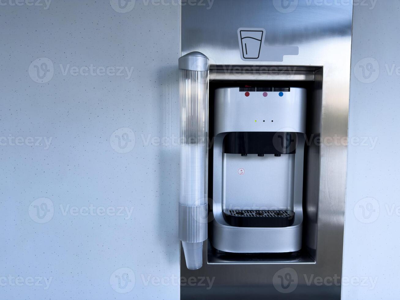 Modern water dispenser with paper cups inside public transportation. Clean and sleek design provides access to hot and cold water for passengers during their journey photo