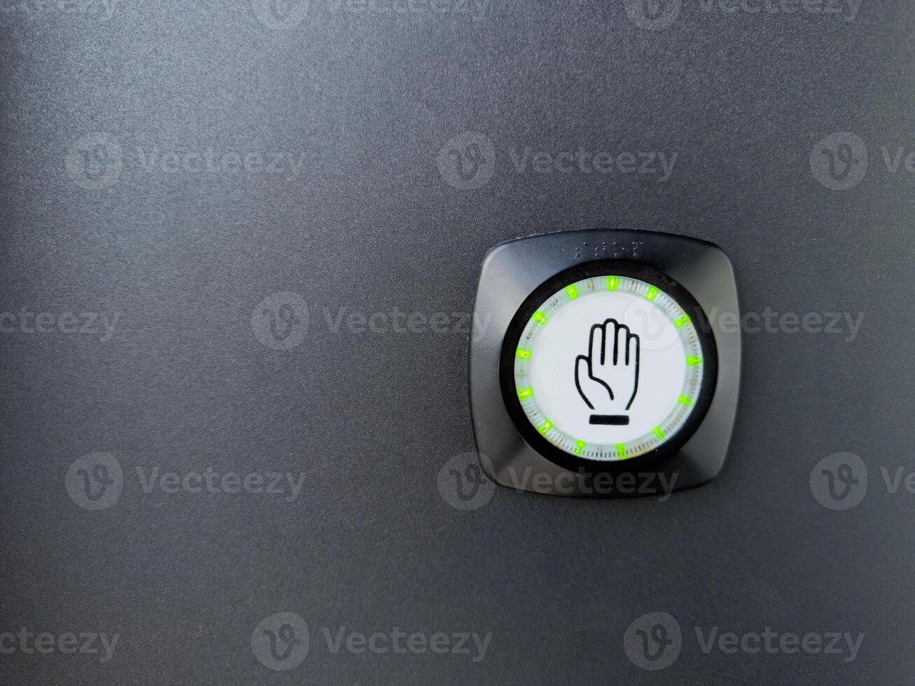 Closeup of touch sensitive button with hand icon and green LED indicators on a black surface. Modern design element often used for contactless door activation or access systems photo