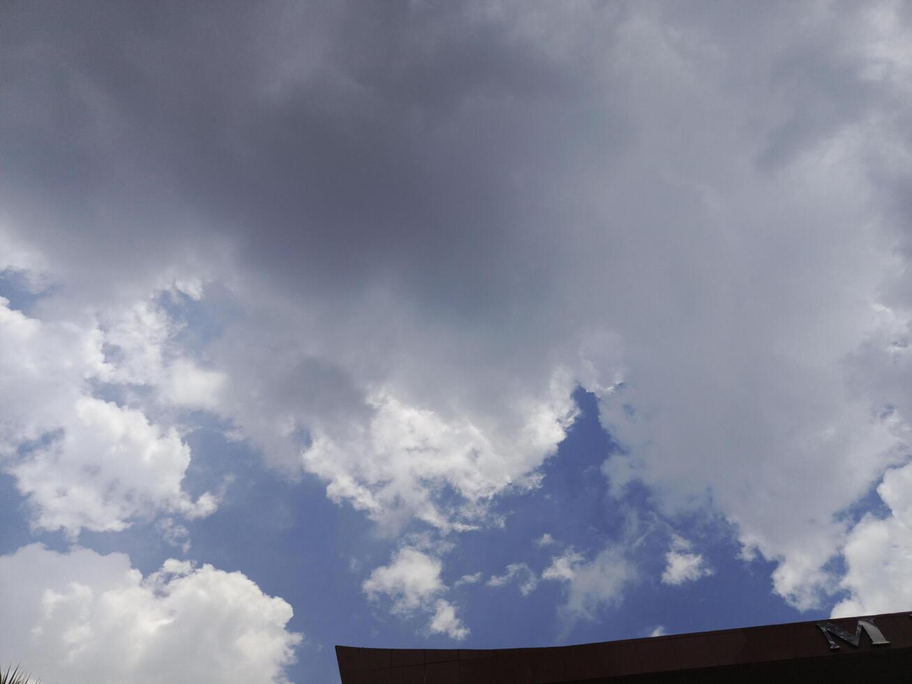 Cloudy Blue Sky with Billowing White Clouds Above Brown Building photo