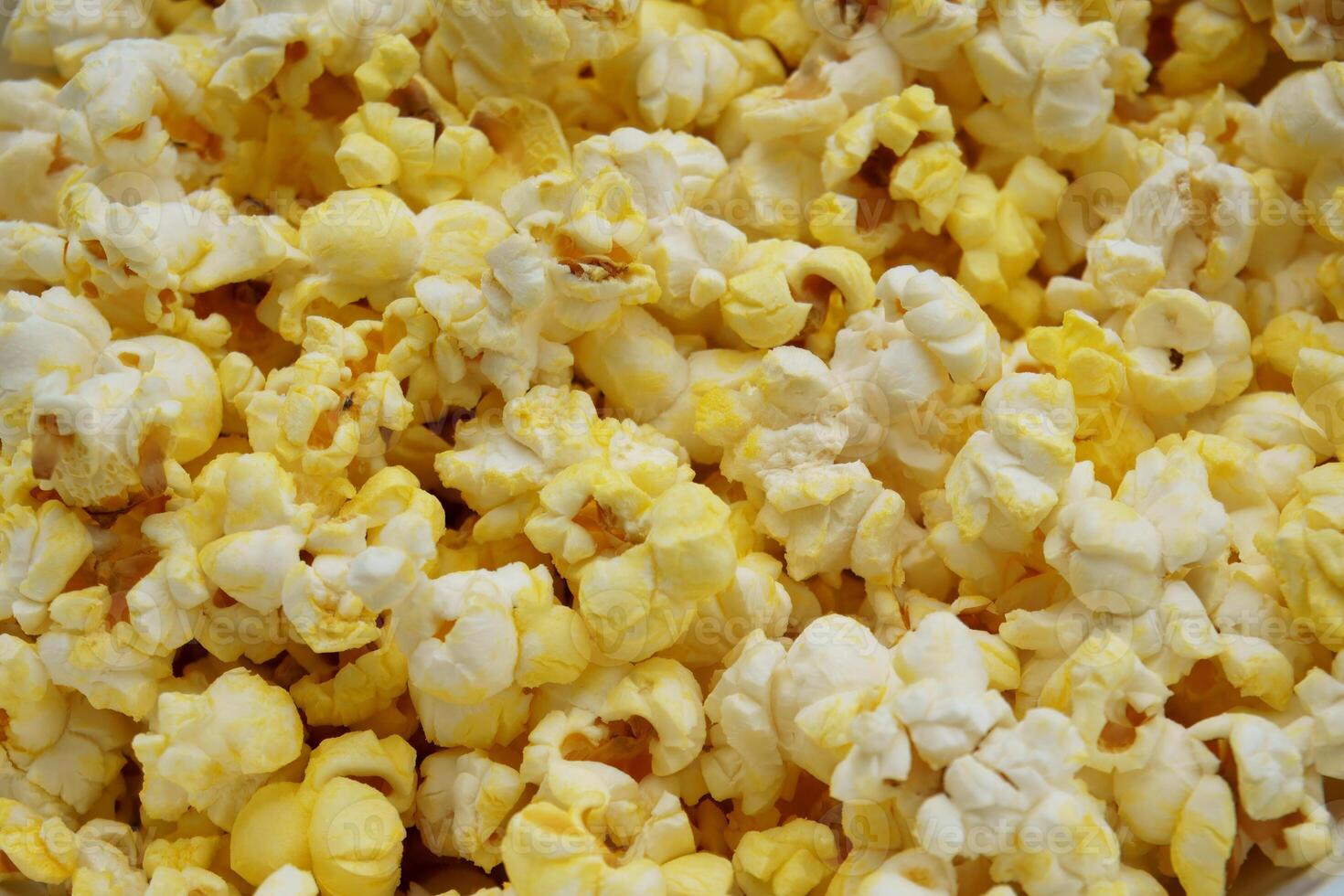 Close-up of freshly popped buttered popcorn. A golden, crispy, and tasty snack ideal for movie nights or food-related content. High-resolution macro image with vibrant yellow and white tones. photo
